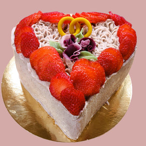eine kleines Tortenherz, es ist eine vegane Erdbeercreme mit Erdbeeren, drei kleinen Rosen und zwei ineinander verschlungenen Ringen dekoriert