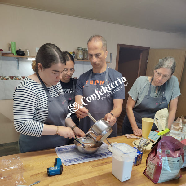 vier Personen stehen am Arbeitstisch und verrühren gemeinsam die verschiedenen Komponenten der Füllung.