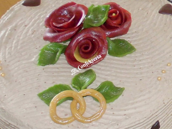 rote Marzipanrosen, grüne Marzipanblätter und zwei verschlungene Marzpanringe dekorieren diese Torte.
