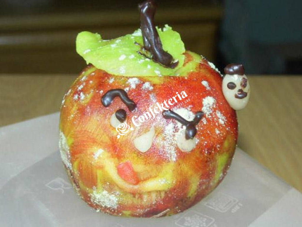 roter Marzipanapfel, er ist mit einem grünen Blatt  und einem Gesicht geschmückt, an der  Seite guckt ein Marzipanwürmchen aus dem Apfel