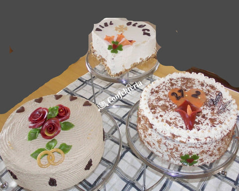 Die hintere Torte ist ein Herz, mit Callas und den Worten: viel Glück. Rechts vorne eine Schwarzwälder Kirschtorte mit feinen Schokospänen. Links vorne Mokkasahne mit roten Marzipanrosen und goldenen Ringen